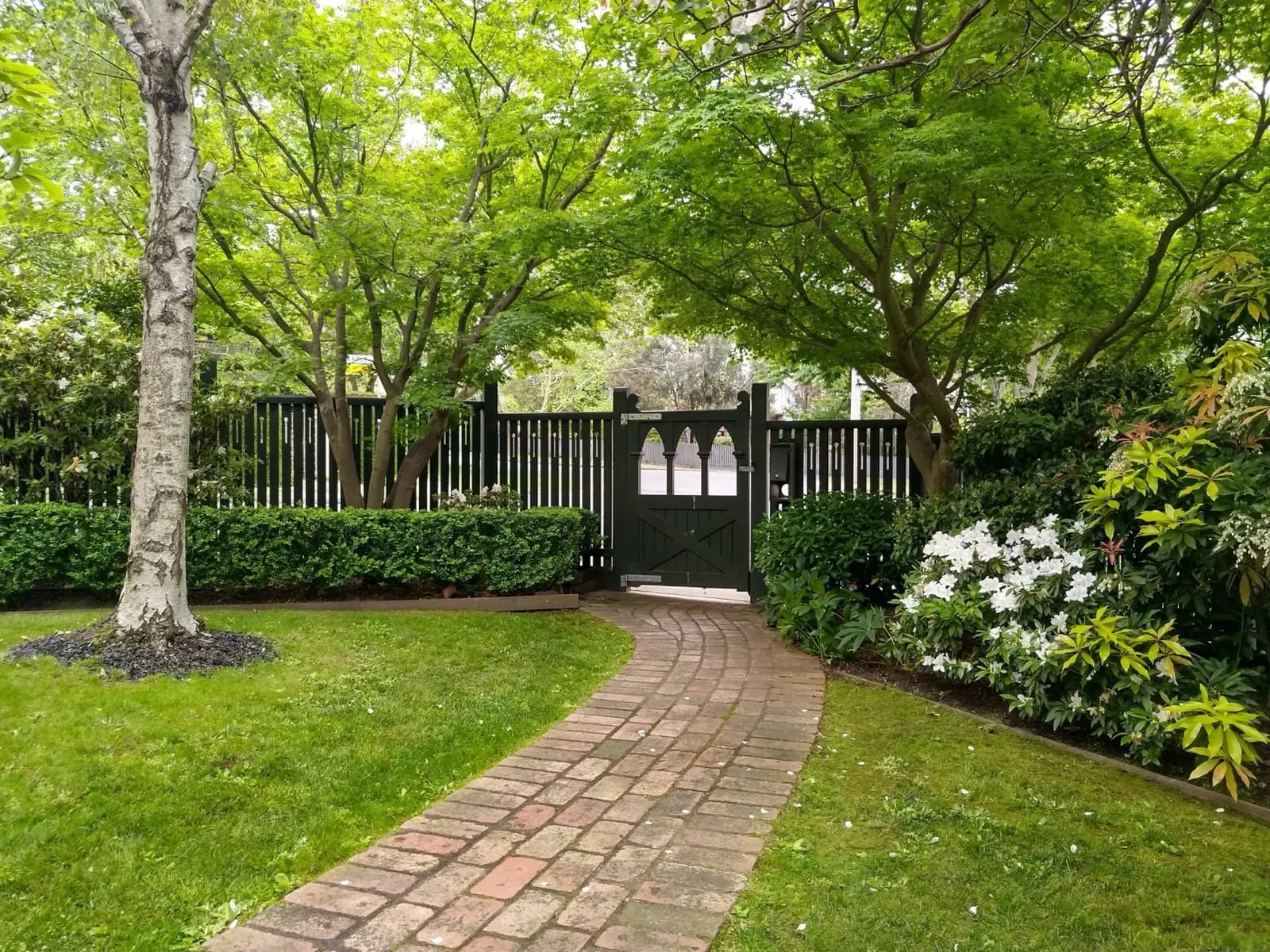 Brick garden pathway through lush green tree canopy maintained by ABS Horticulture in Melbourne's eastern suburbs